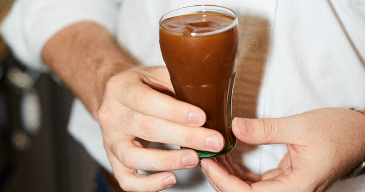 Someone holding a Ron Con Cola, a brown colored cocktail
