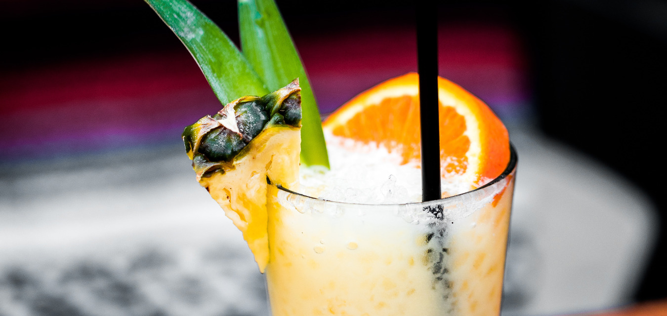 Piña colata in a tall glass garnished with an orange slice and a pineapple slice