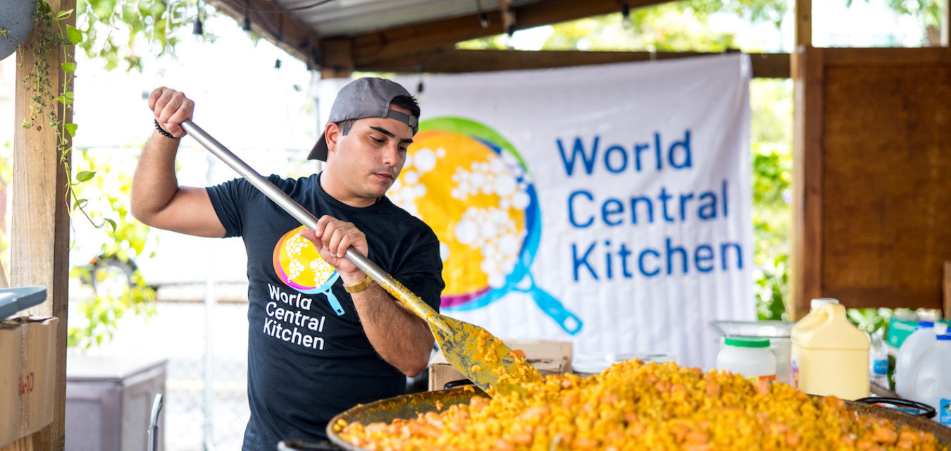 World Central Kitchen volunteer heating a large amount of food on a large skillet