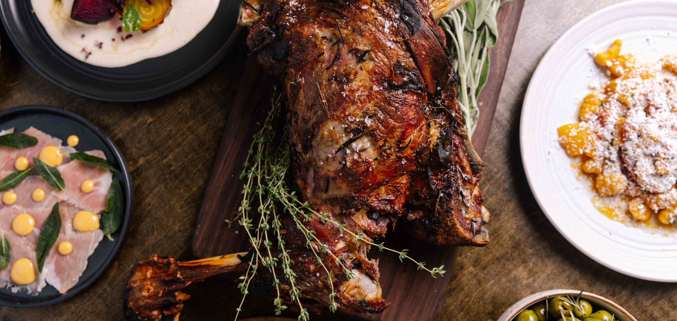 Whole roasted lamb on a board, garnished with thyme and sage
