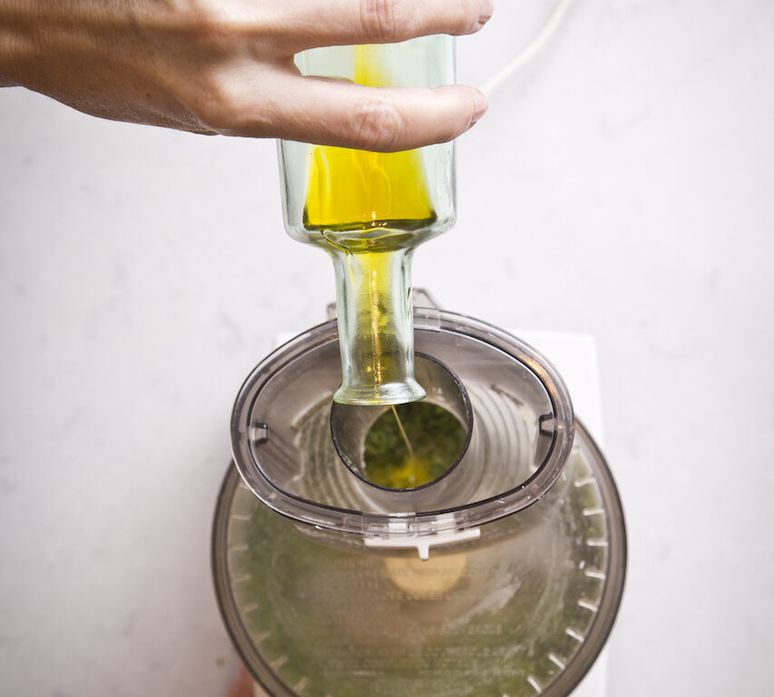 Adding oil to food processor with pesto