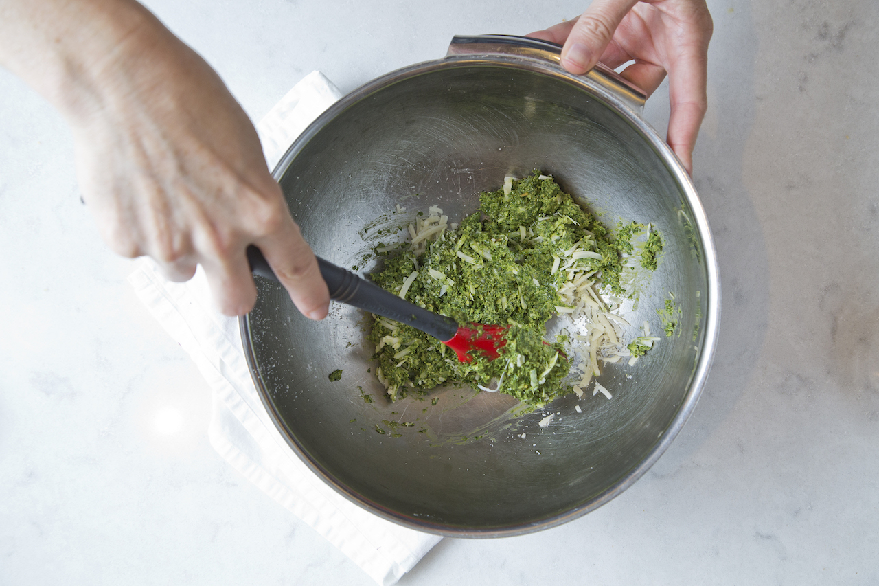 stirring in Parmesan cheese to pesto