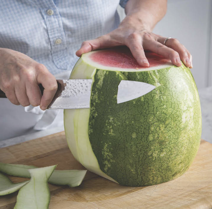 Someone cutting ends from watermelon and removing green outer skin for the pickled watermelon rinds