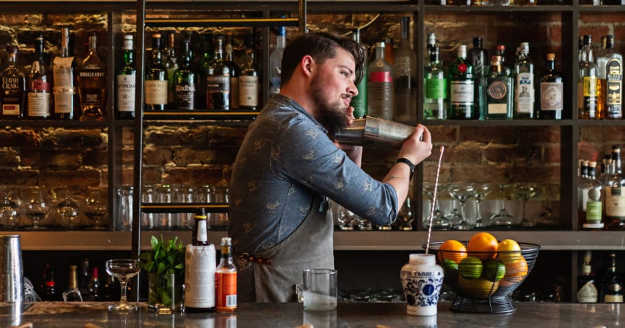 Andy Bixby preparing whiskey cocktails behind the bar.