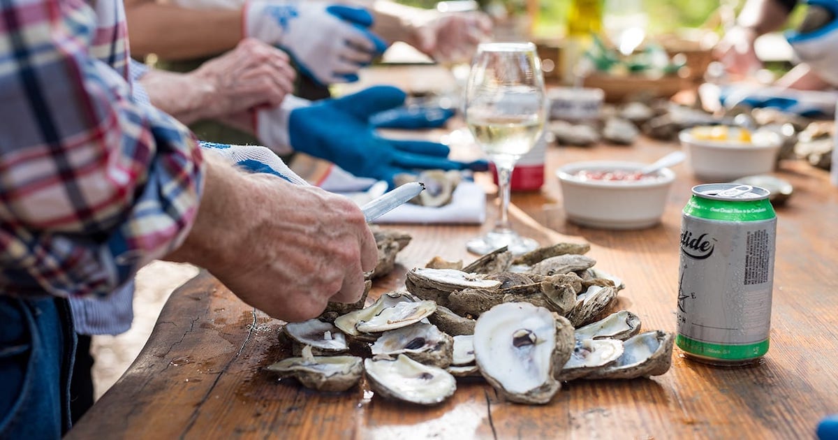 Hands together on a table shucking oysters