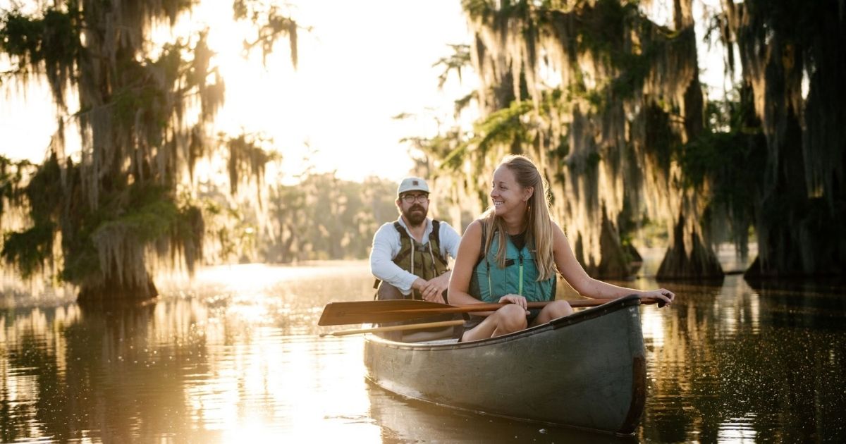 A couple paddle in a canoe in the marshes through Lafayette Lousiana