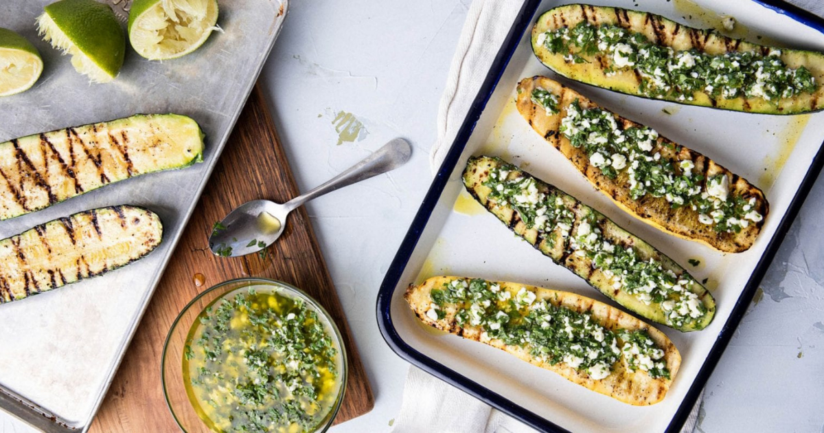 Grilled zucchini on a sheet tray topped with chimichurri