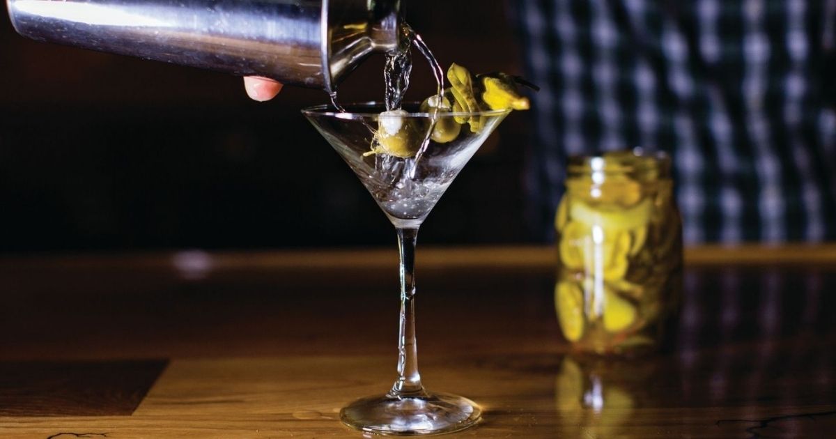 pouring a dirty martini into a glass