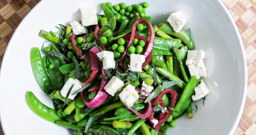 Bowl of asparagus and pea salad with chunks of feta