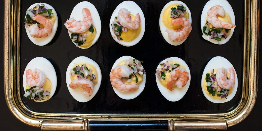 Tray of deviled eggs topped with pickled shrimp