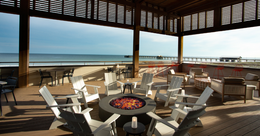 Outdoor seating at Perch Restaurant at the Lodge at Gulf State Park, where chairs surround a fire pit and the beach is visible