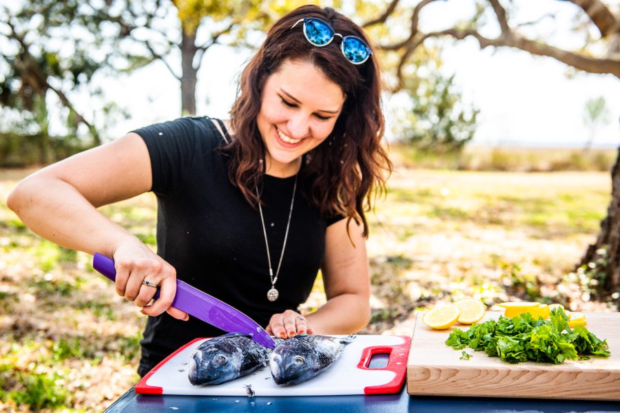 Lia scales and filets fish for her camping recipes