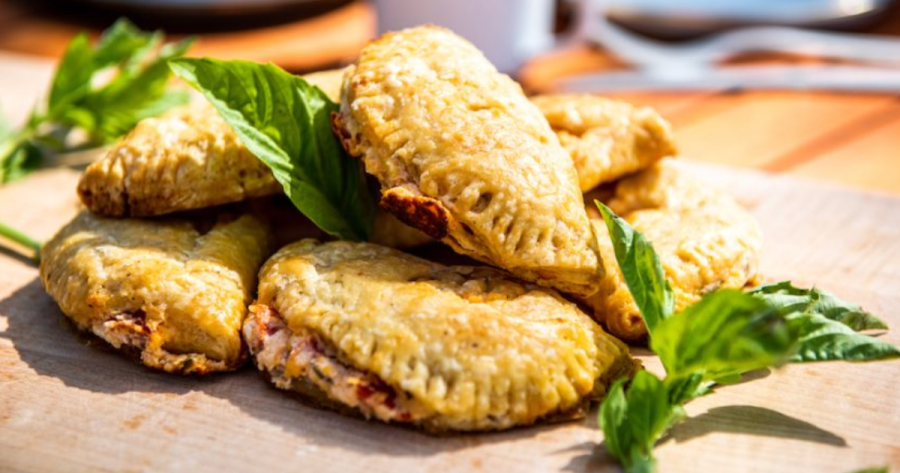 Photograph of a pile of savory hand pies on a cutting board, a camping food