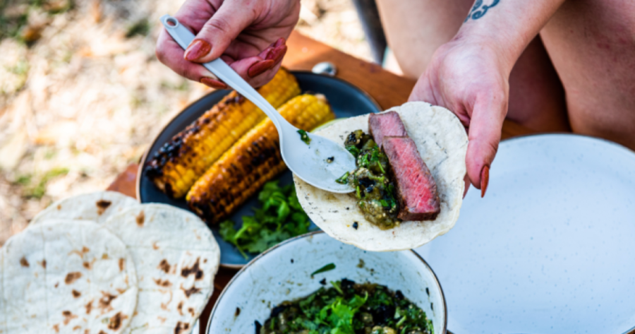 Photograph of a steak taco being assembled with sauce, a camping food