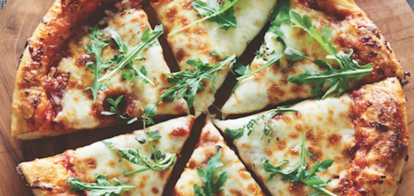 Photograph of the pizza crust recipe finished and baked with cheese and arugula on top