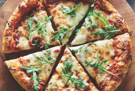 photograph of pizza crust recipe finished with cheese and arugula topped on it