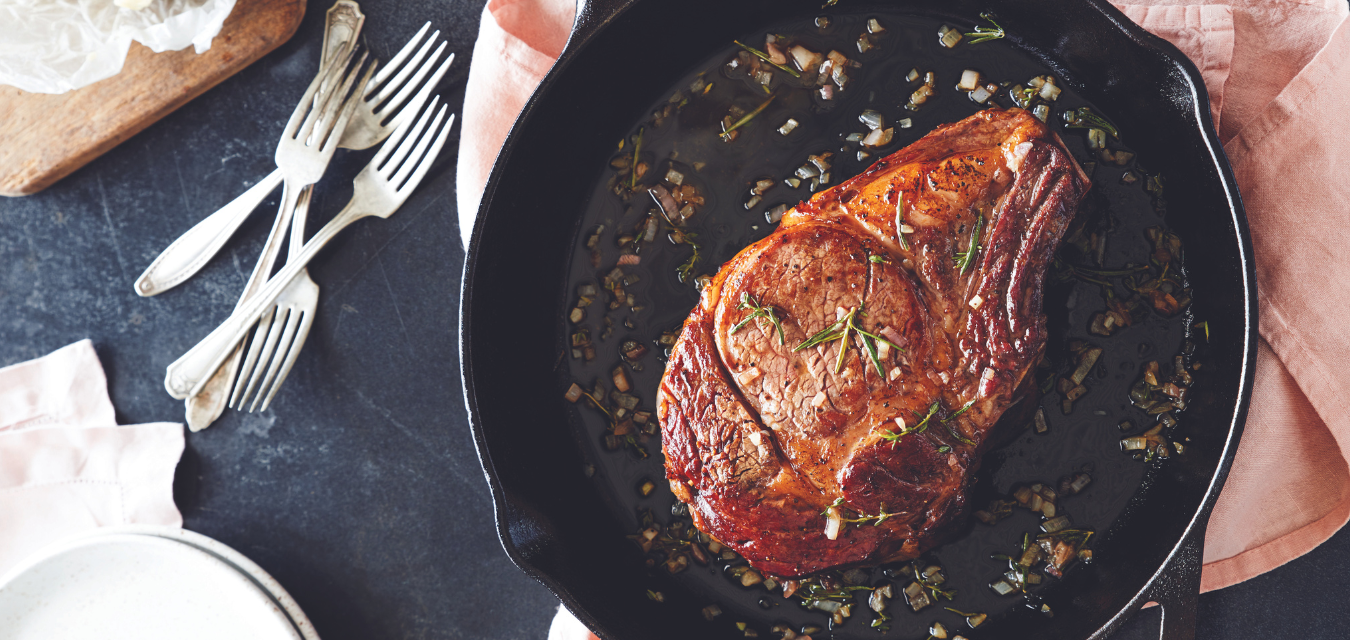 Photograph of this finished steak recipe in a skillet with the pan sauce over top