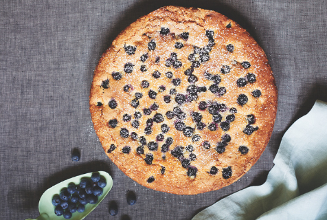 Photograph of this finished blueberry and lemon ricotta cake with a scoop of blueberries being served on the side