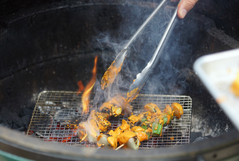 Photograph of food being grilled with tongs flipping them at Goodyear House, which is where to eat in Charlotte