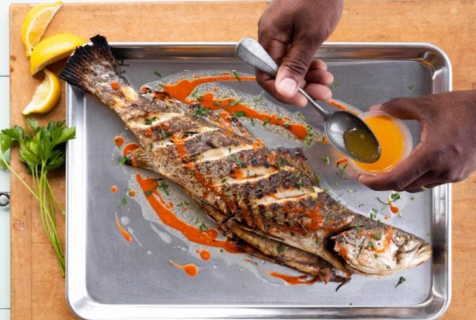 Photograph of a man topping a fish with a sauce on a metal tray showcasing where to eat in North Carolina
