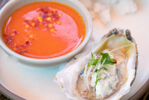 Photograph of oysters on ice besides an Italian dipping sauce