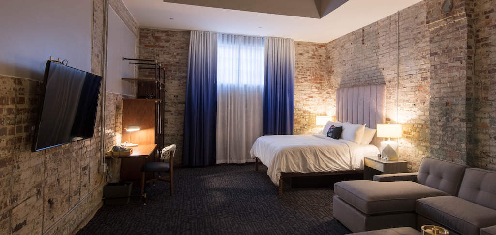 Guest room in Hotel Trundle with exposed brick walls and blue curtains