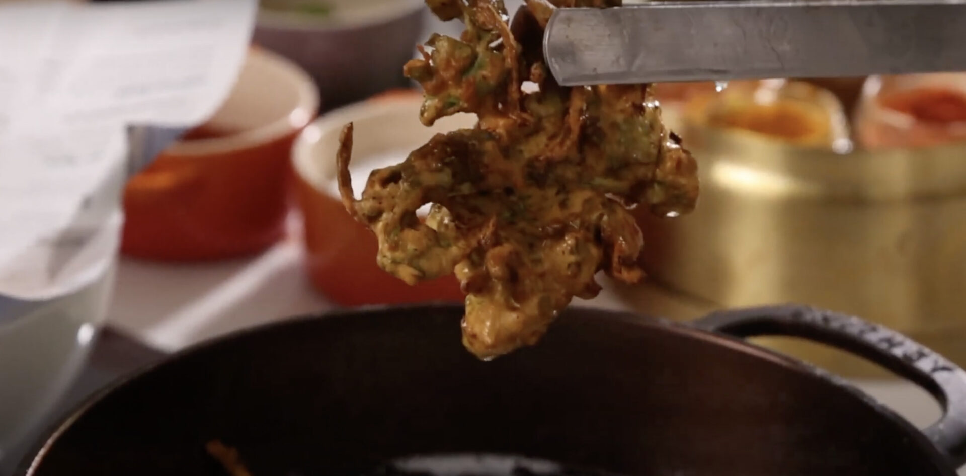 Pulling fried vegetable pakora out of frying oil