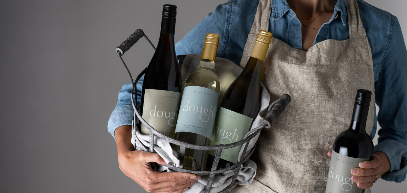A woman holds a basket of Dough Wines bottles, part of the Holiday wines that give back.