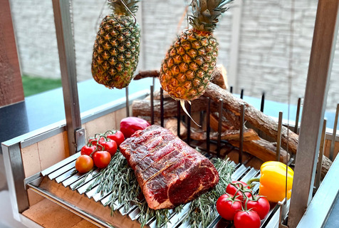 Pineapples, tomatoes, beef grilling on the asado