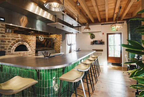 Southbound's chefs counter is an emerald green bar with tall chairs around it overlooking the wood-fired hearth kitchen at this recently opened restaurant. 