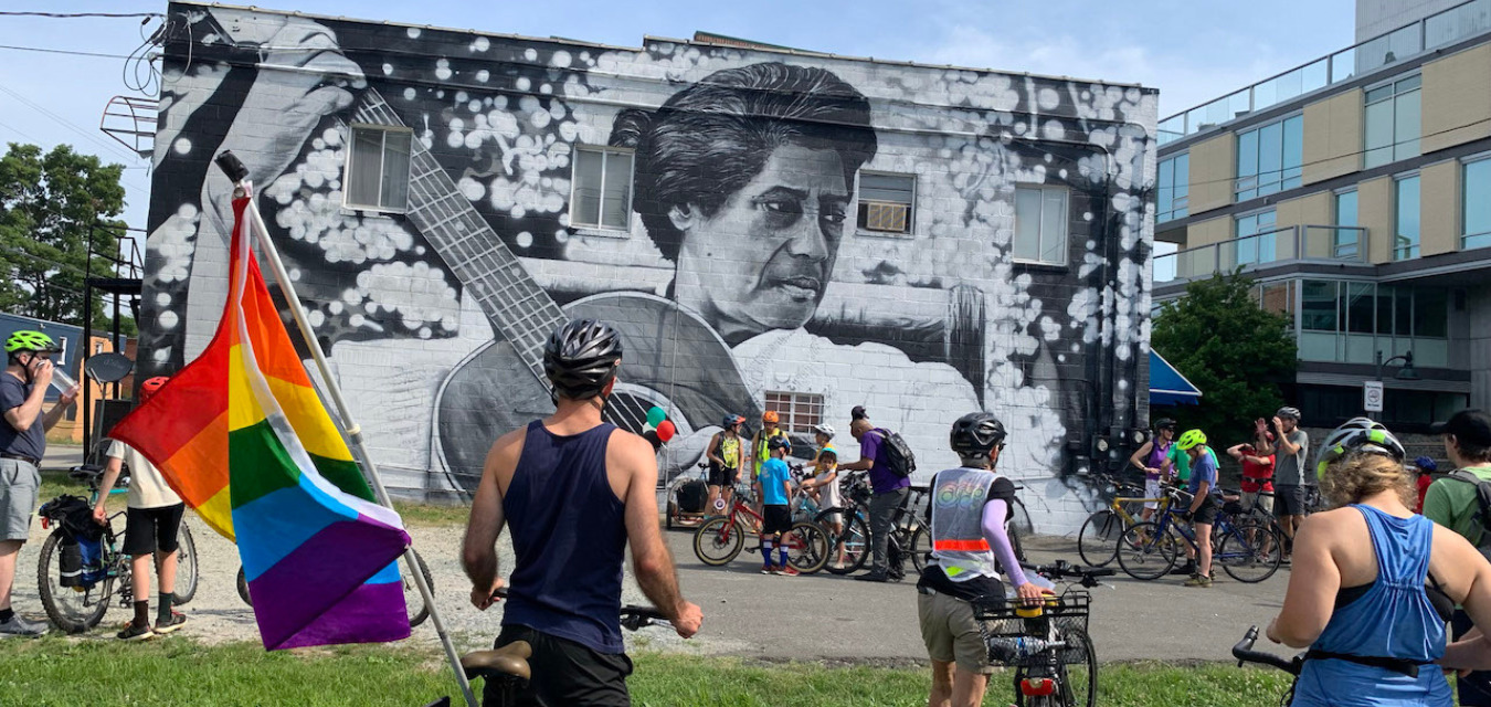 Pride cyclists in front of a mural in Carrboro North Carolina
