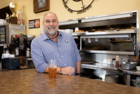Mississippi restaurateur Robert St. John leaning on a counter and smiling. 