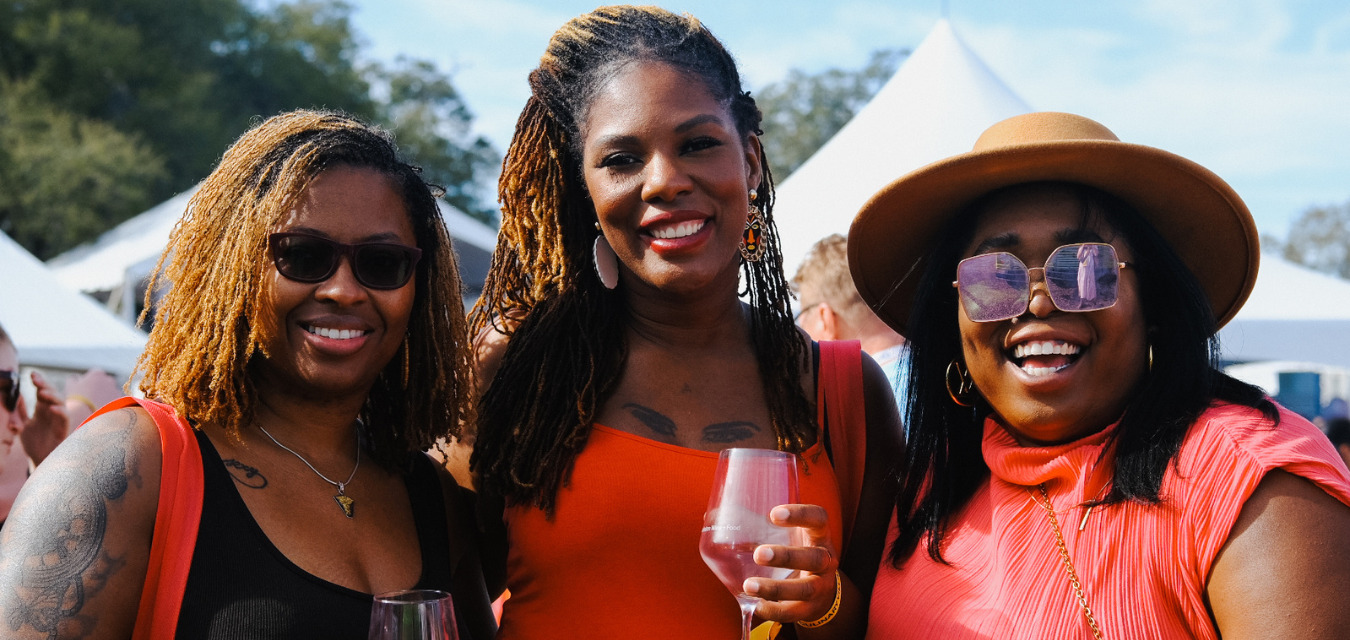 Three women outdoors drinking glasses of wine on a sunny day at the Charleston Food and Wine Festival.