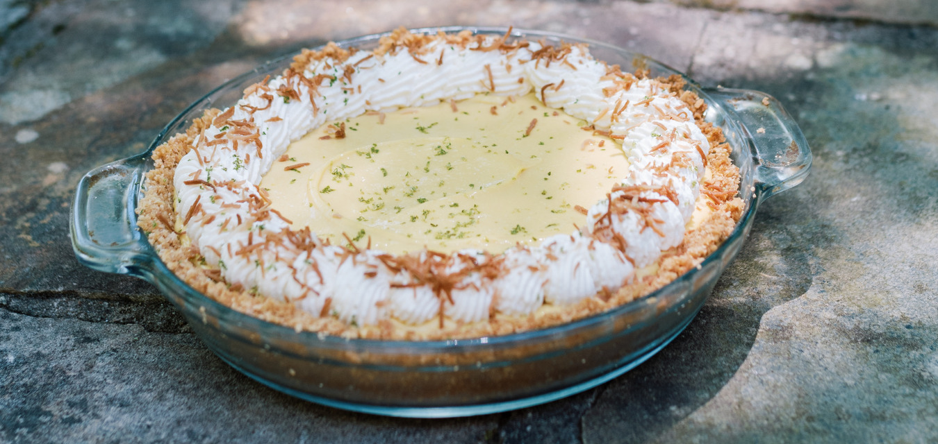 A completed Gulf Beach Pie with yellow filling, crumble crust and whipped cream