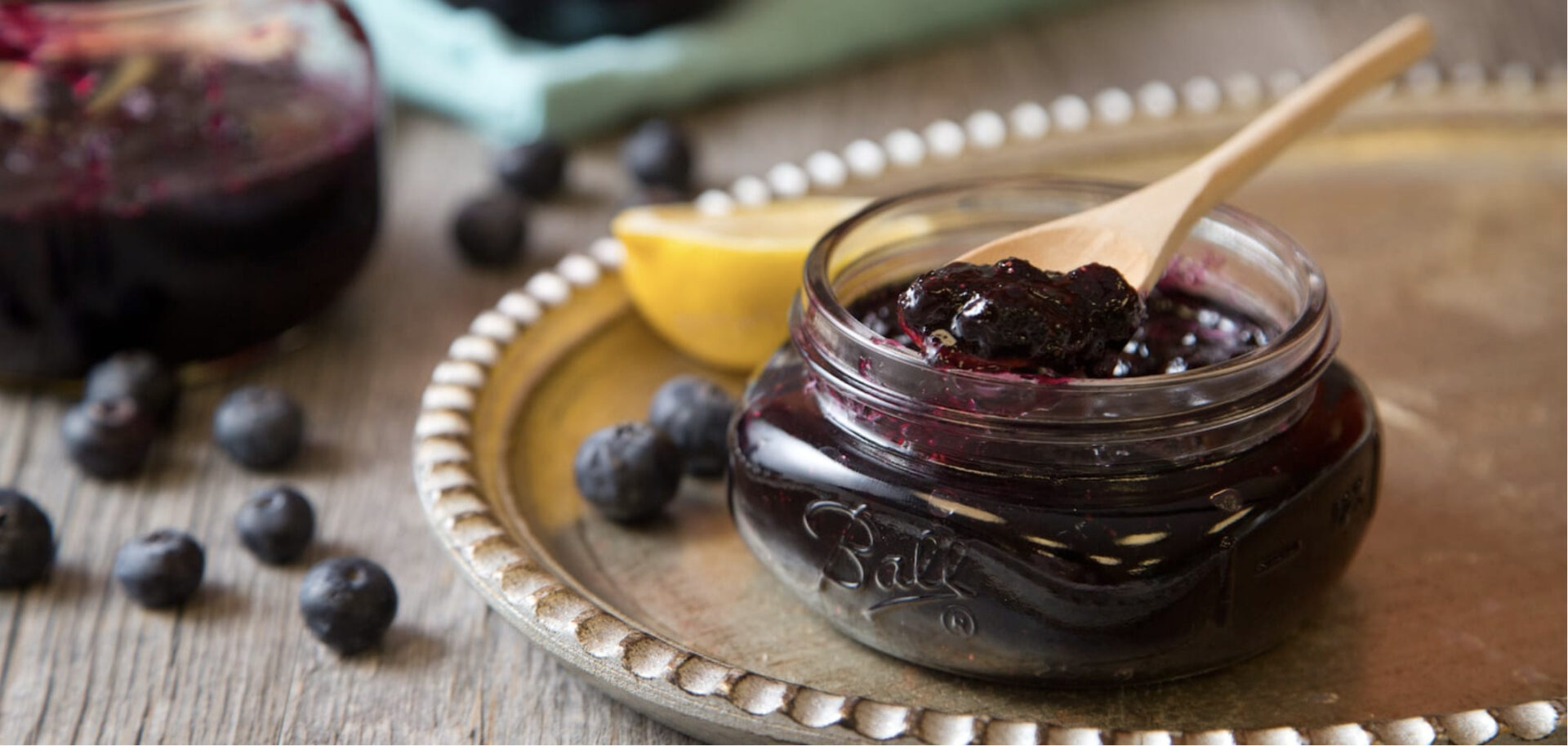 Homemade Blueberry Jam in a glass jar with lemons and blueberries around it