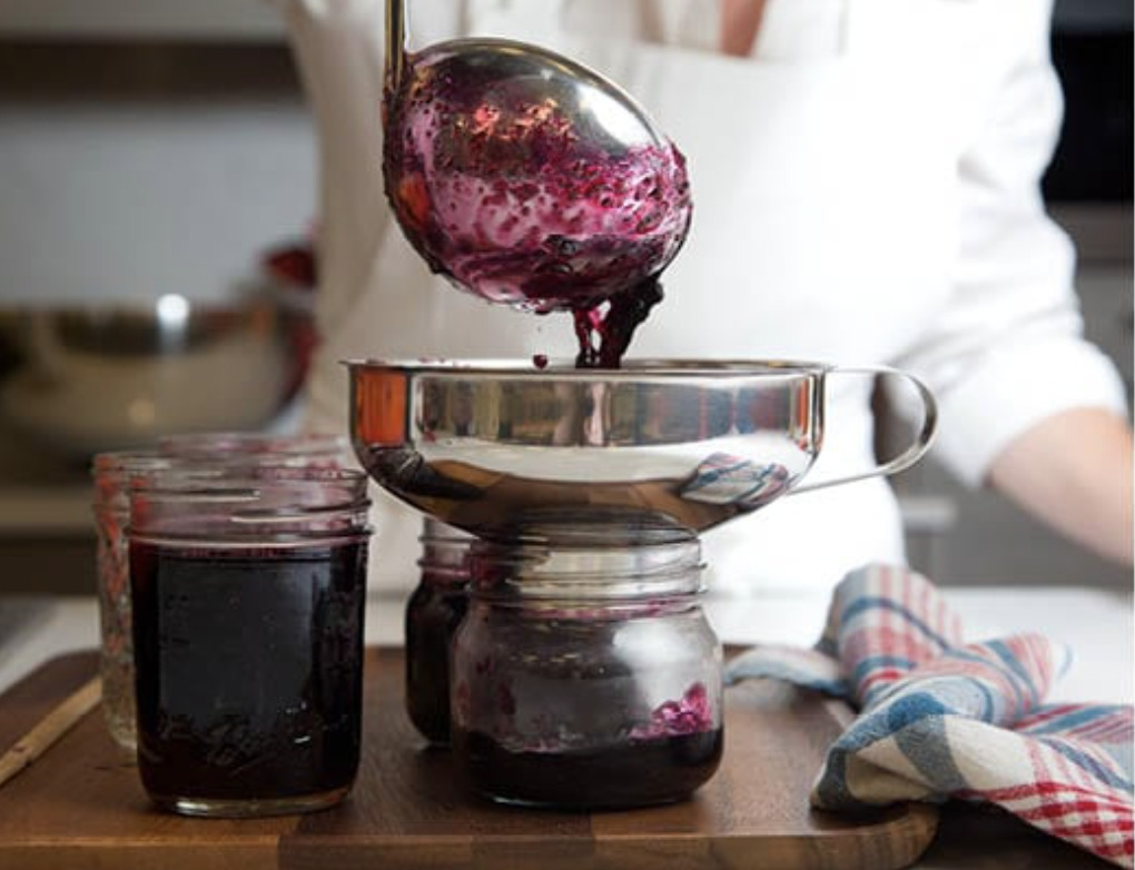 The homemade jam is ladled into the jars for sealing.