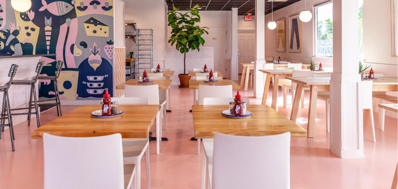 Hungry Pants interior with pink floors, white chairs and globe lights. Hungry Pants is a plant-based eatery in Orlando