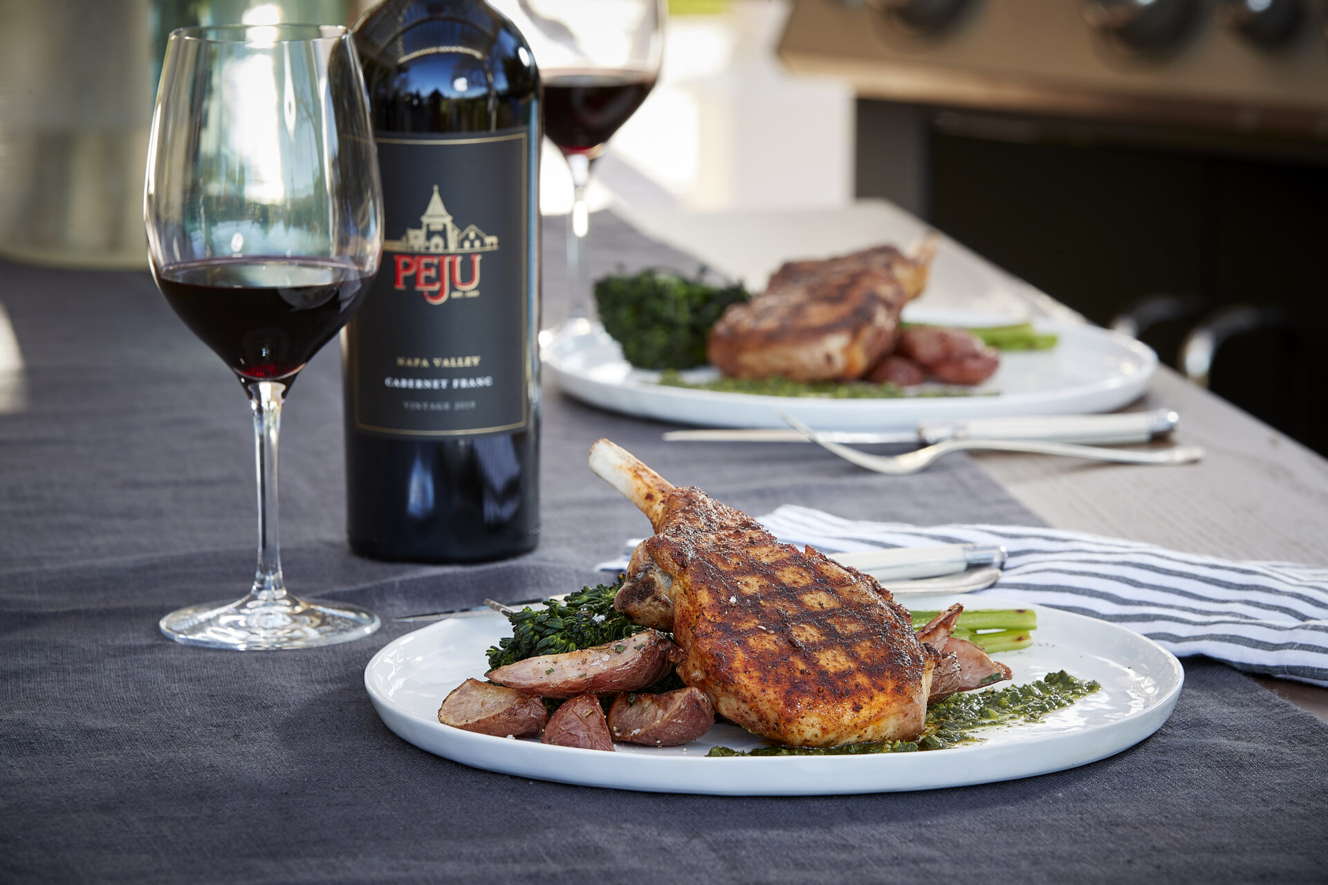 Peju Winery's BBQ duo bottle and glass with a porkchop and sides on a plate