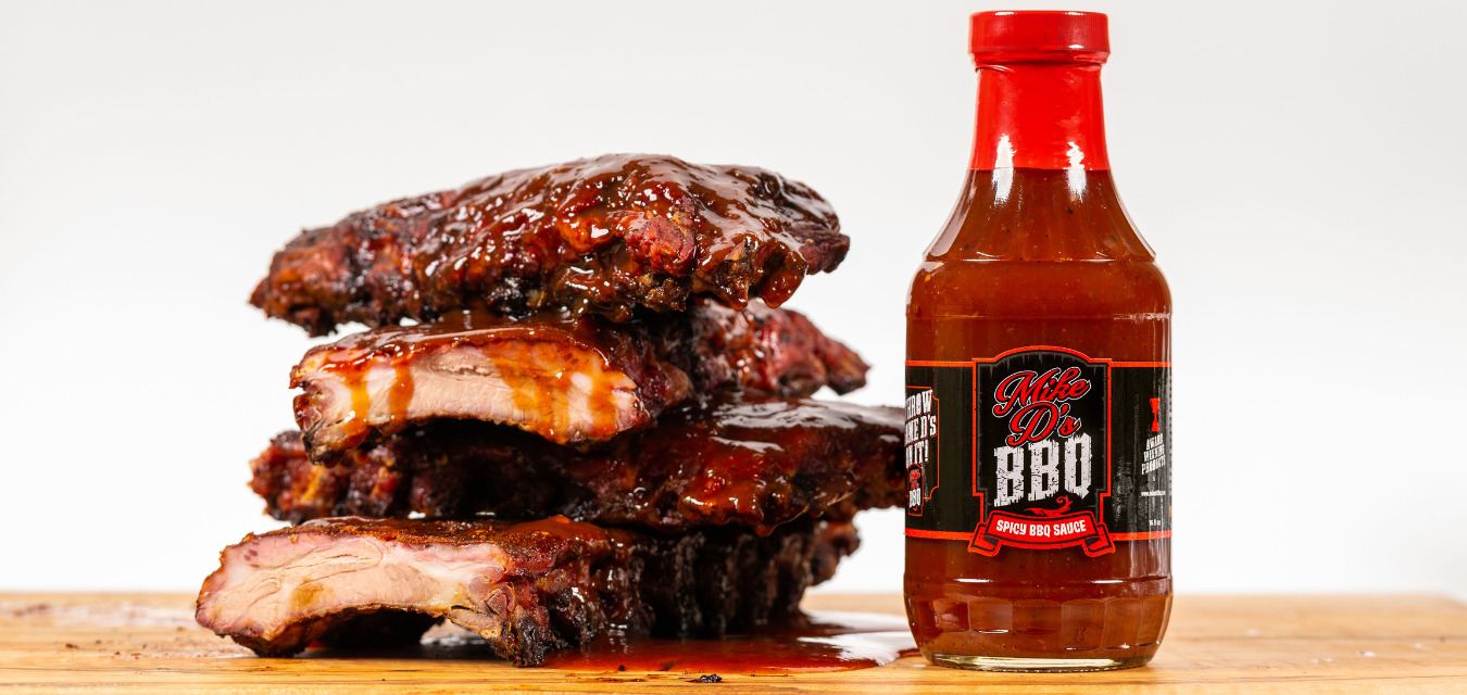 Mike D's Smoked Ribs with a bottle of Mike D's sauce next to it on a cutting board.