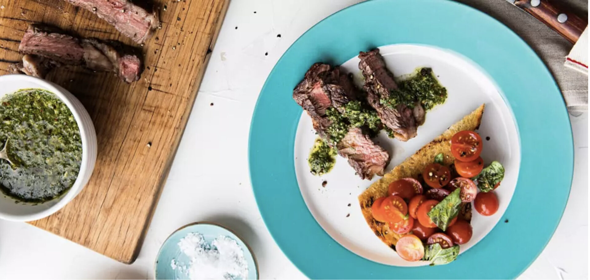 Ribeye with Chimichurri on a blue and white plate, served with grilled bread tomato and basil, one of four Father's day ideas for meals