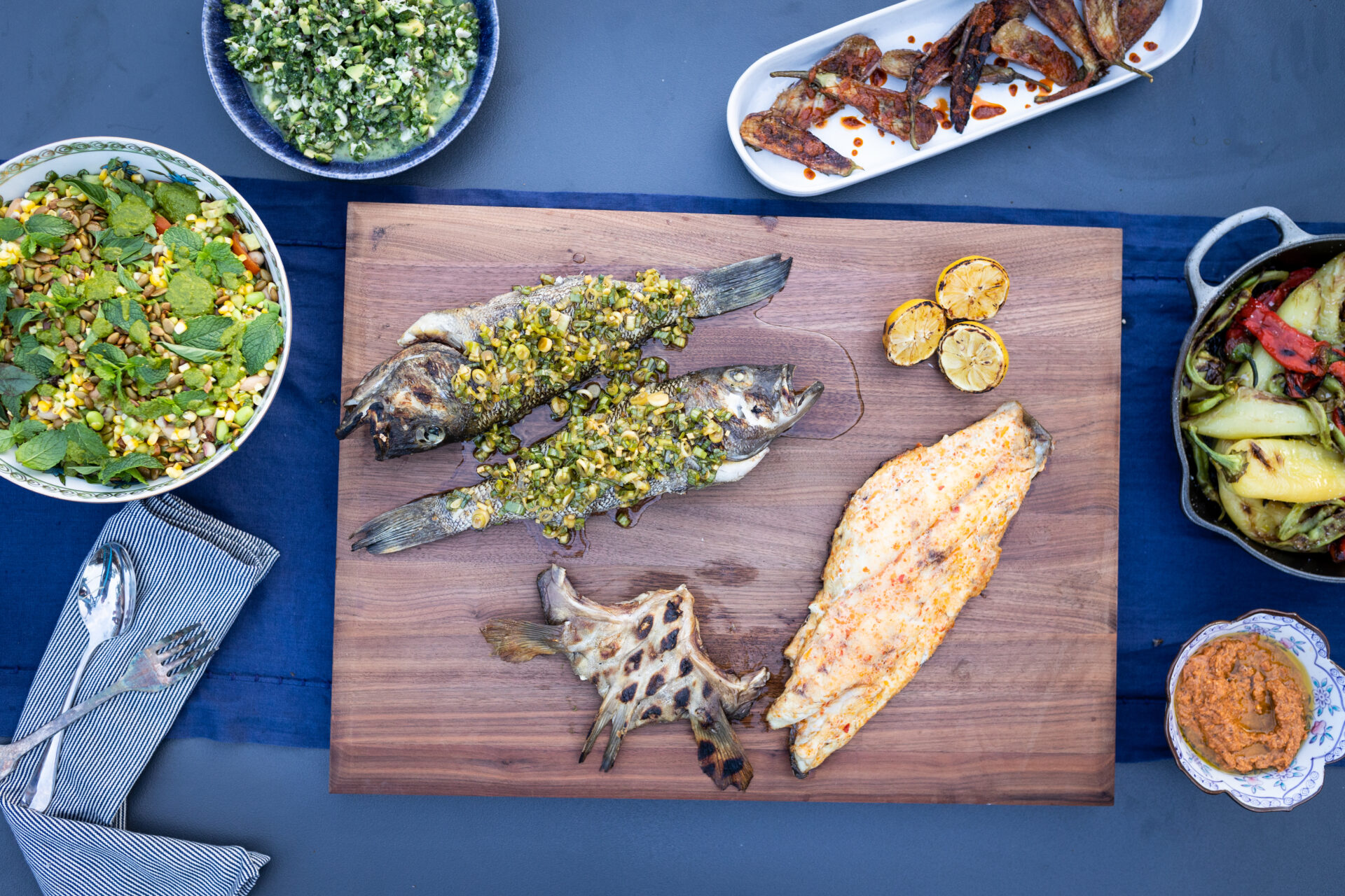 A table spread with whole fish, fillets, a salad, and spread for an intimate dinner