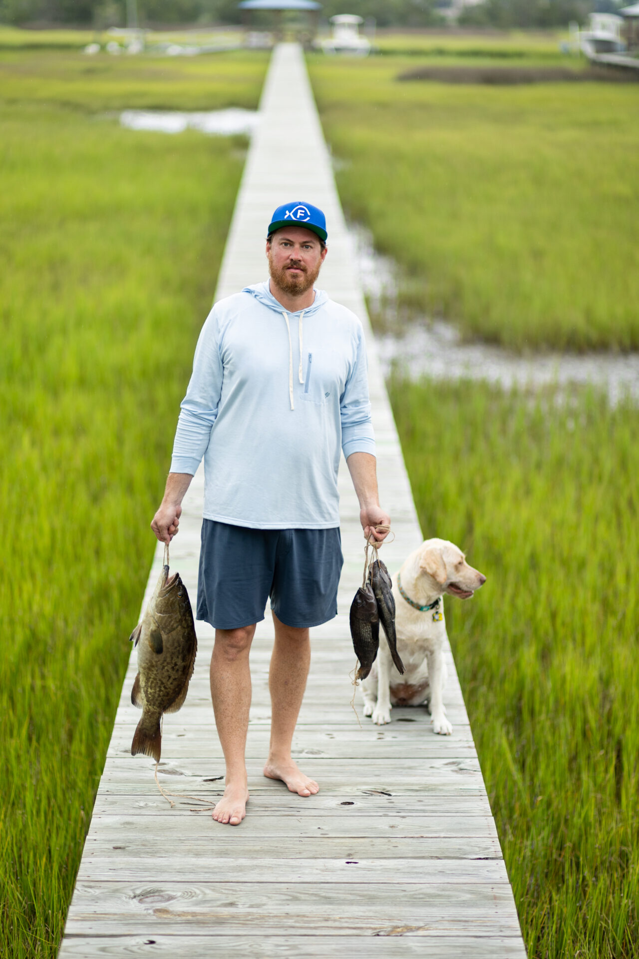 James London of Chubby Fish carrying fresh-caught fish with his dog beside him