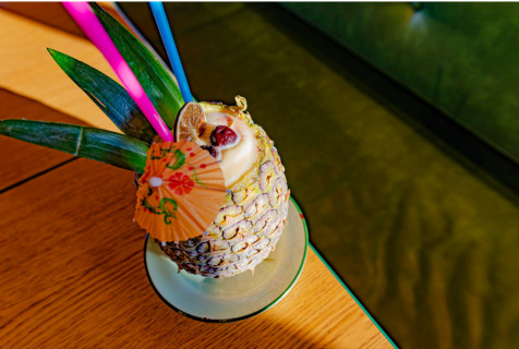 The Double Vision Cocktail. A pina colada style drink served in a pineapple with a tiny umbrella and colorful straws from Camp Taco in Little Rock