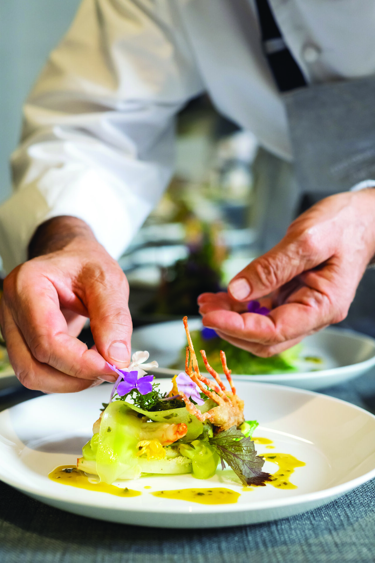 A chef is decorating the food of a dish.