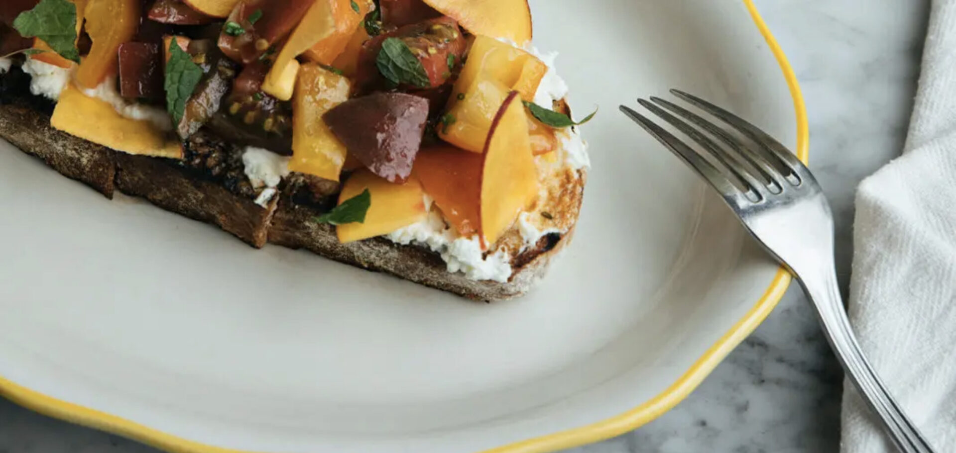 peach and tomato on toast with a fork next to it