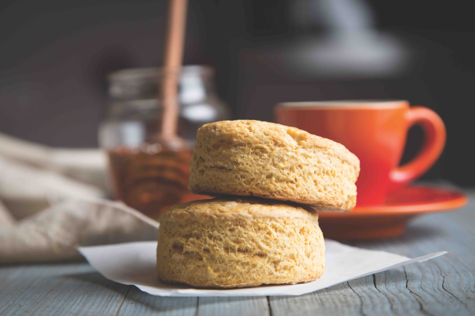 Sweet potato biscuits, one of Cheryl Day's brunch recipes, an orange cup of coffee and honey lie in the background