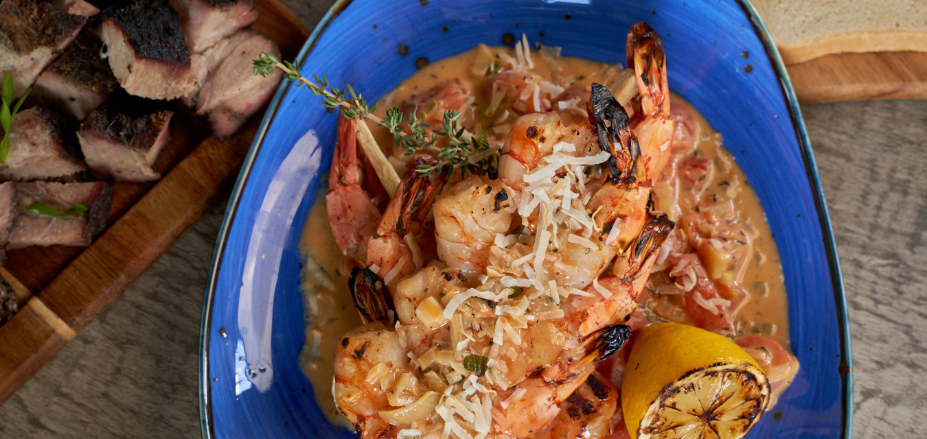 Lemongrass shrimp skewers served with sauce and rice in a blue plate