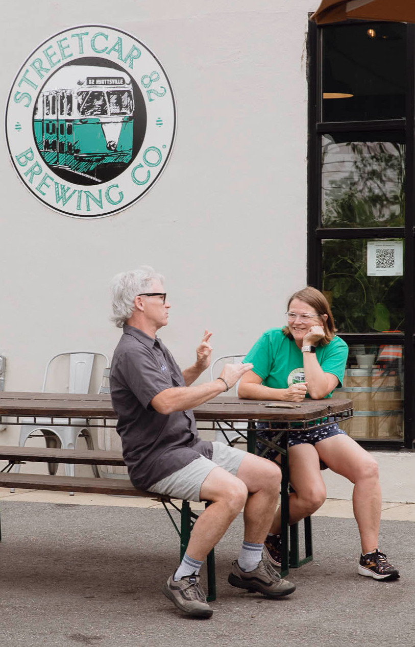 Mark Burke, one of the cofounders of Streetcar 82 Brewing, signing with a customer outside on a picnic table.