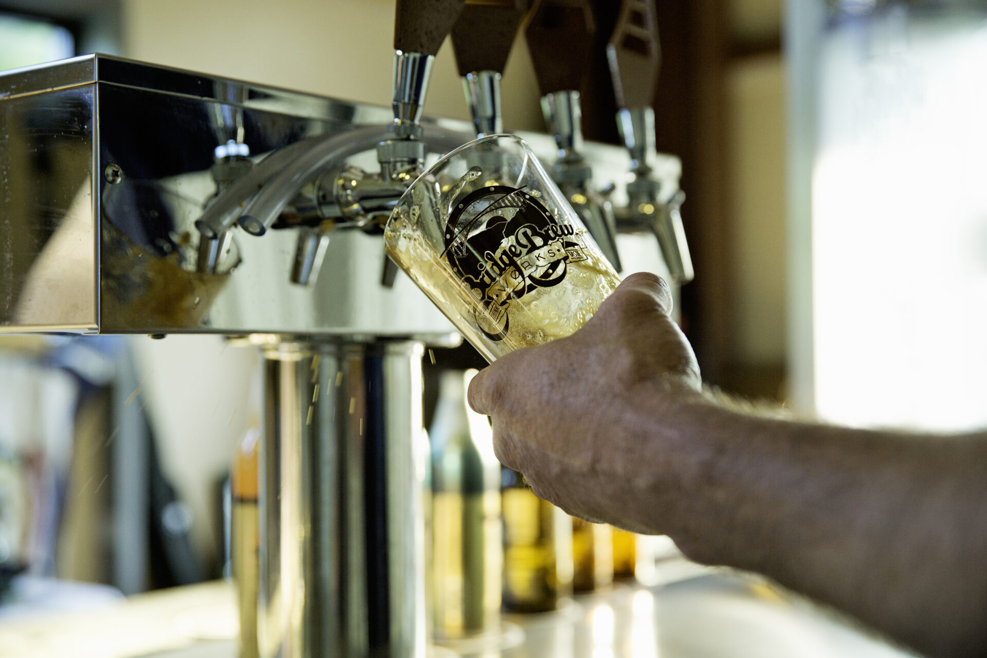 A image of a man holding a glass under a tap, pouring a beer at Bridge  Brew Works in Charleston, West Virginia.