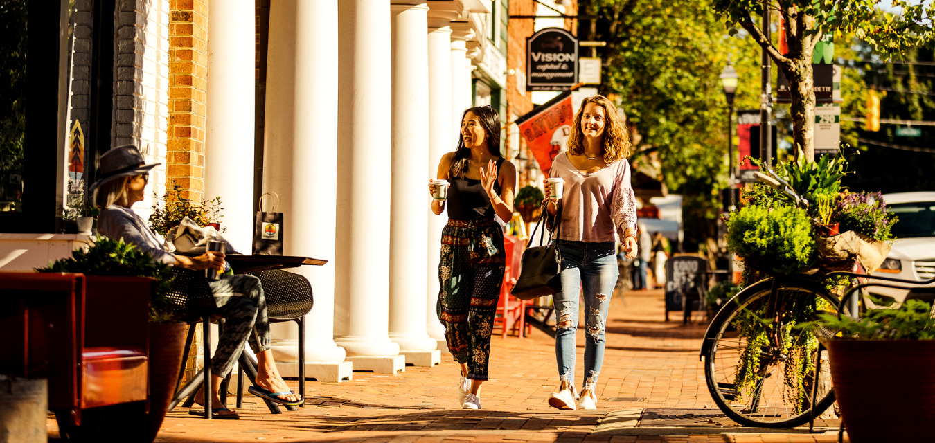 Students walking down a busy street holding coffees near Davidson College in Lake Norman.